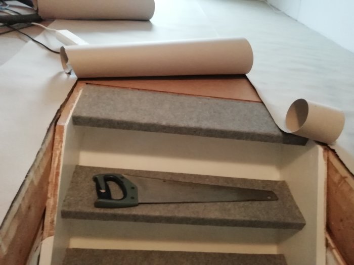 Öppen trappa redo för laminatläggning, med verktyg och golvmaterial på plats.