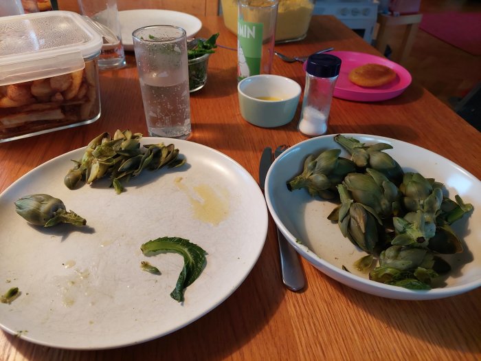 Skördade små kronärtskockor på en middagstallrik vid ett köksbord.