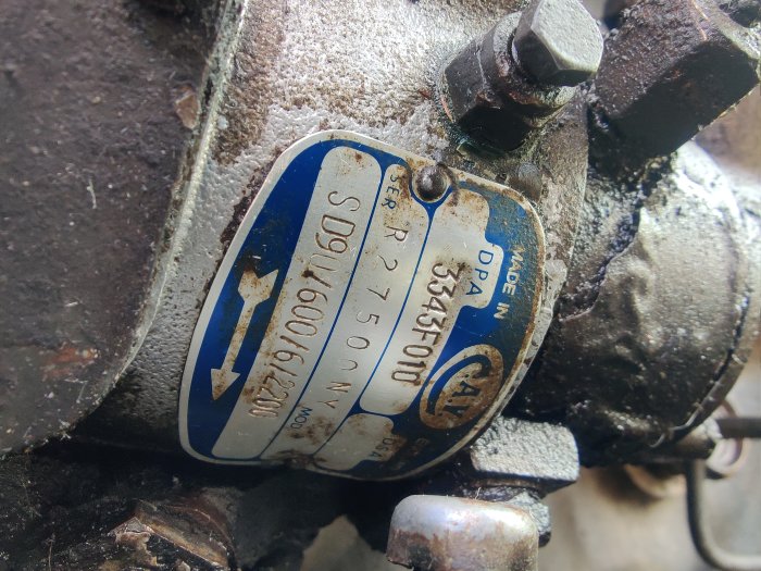 Närbild av ett smutsigt massey ferguson gasreglage på en dieselpump med en ren märkskylt.