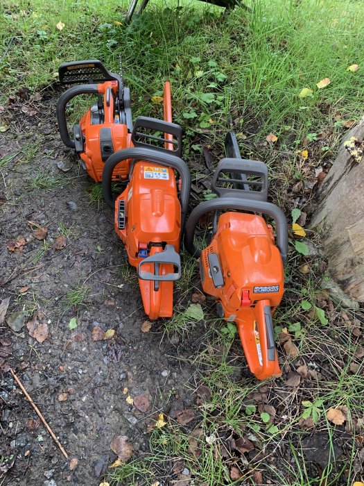 Tre nyligen underhållna och slipade motorsågar uppställda på marken utomhus.