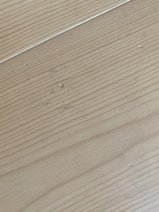 Vitvaxat furugolv med synliga repor och en skarv mellan brädorna.