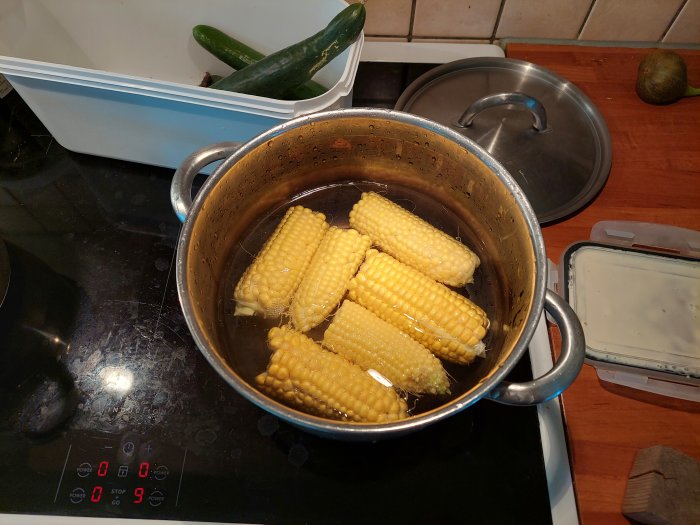 Egenodlad majs som kokas i en kastrull på spisen med synliga grönsaker i bakgrunden.