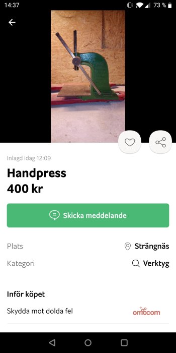 Grön handpressverktyg mot plywoodbakgrund, annonserad för försäljning.