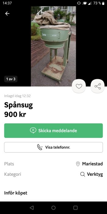 Äldre grönmålad spånsugsmaskin av märket Luna står på en trottoar med en tygsäck uppepå.