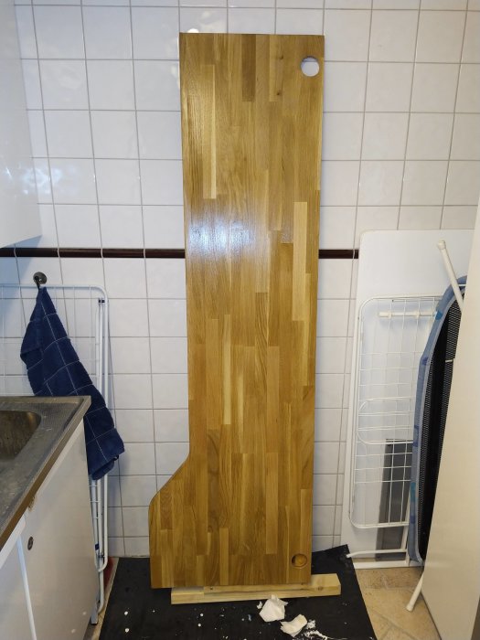 Grovpassad limfogskiva i ek står i ett badrum, lackad och redo för ytterligare slipning och lackning.