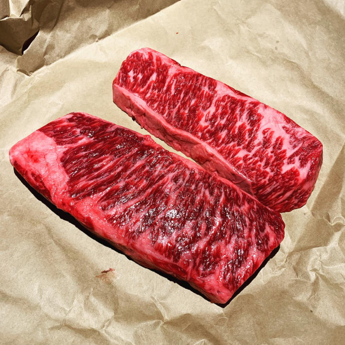 Två stycken rött och marmorerat zabuton kött placerade på brunt papper.