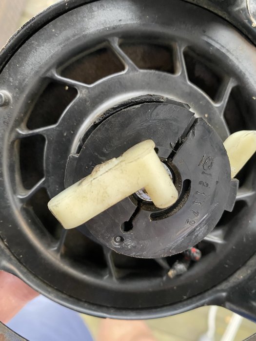 Närbild på en lös komponent i ett startmekanismhus med synliga slitage.