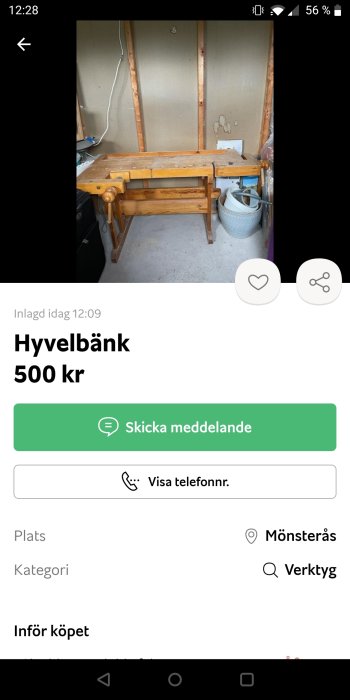 En hyvelbänk i trä mot en vägg i en verkstad med diverse föremål i bakgrunden.