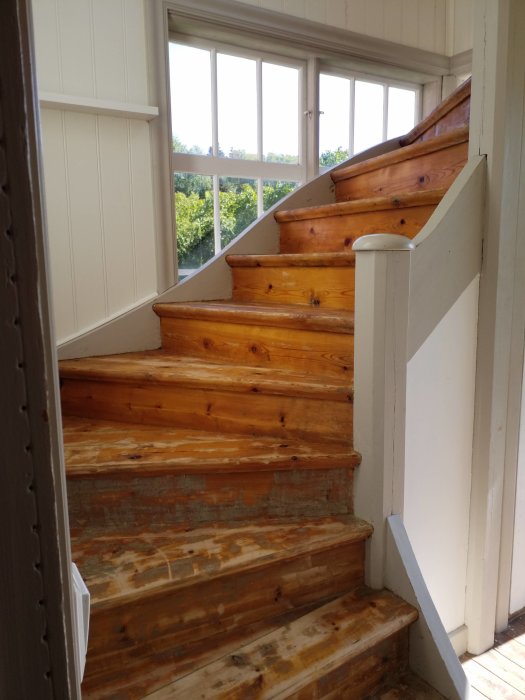 Trappa i en oisolerad farstu i ett hus från 1929 med stora fönster och trästeg.