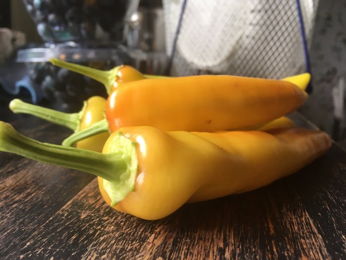 Nyss skördade gula Hungarian Hot Wax chilifrukter på ett träbord.