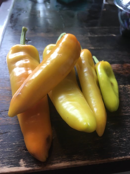 Gula Hungarian Hot Wax-chilipeppar på ett mörkt träbord, redo för inläggning.