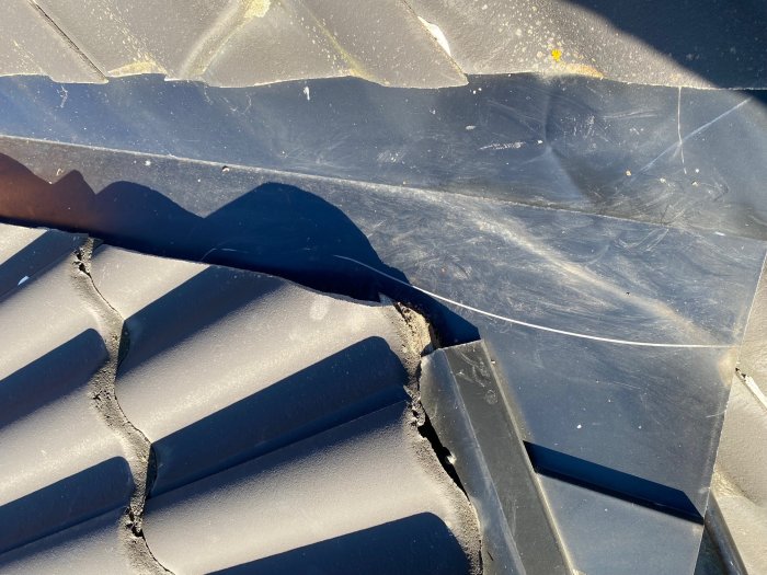 Illa åtgången läkt i en ränndal på ett tak, med synliga sprickor och slitage, ingen tätning mot takpannorna.