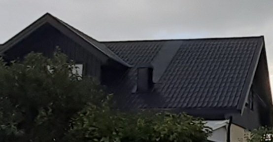Plåttak på hus med ventilationstrumma nära nocken, exemplifierar byggprincip för takhuvar.