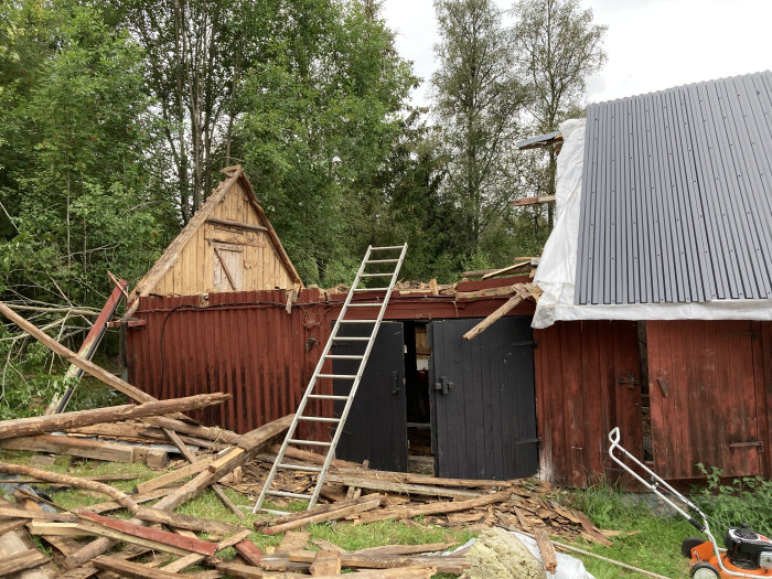 Delvis renoverad ladugård med ny plåt på ena takhalvan och riven konstruktion på den andra.