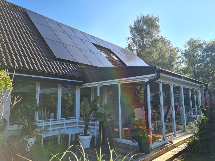 Hus med soldäck och carport med glastak samt solpaneler på taket.