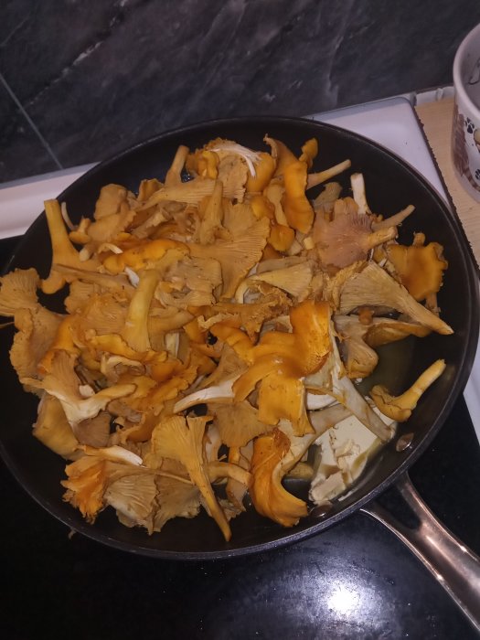 Färska kantareller i en stekpanna, redo för matlagning.