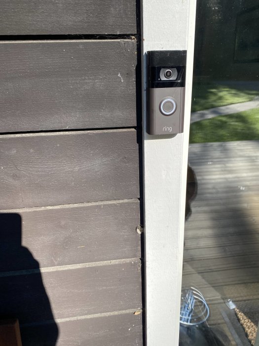 En batteridriven Ring-dörrklocka monterad på en husvägg med ett PVC-rör nedanför.