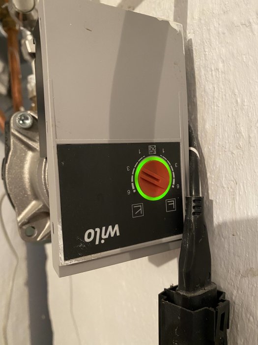 Golvvärmepump med inställningsratt och statusindikatorer på en vägg.