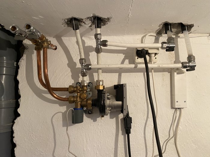 Installation för golvvärmepump och fjärrvärmecentral i ett hem, med rör och ventiler.