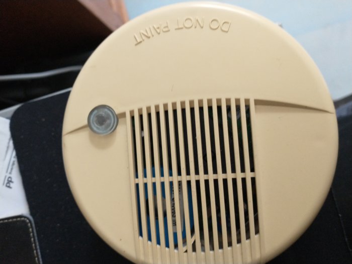 Närbild på en beige rökdetektor, modell WLS-906-NB-434 EU, med tydliga ventilationsgaller.