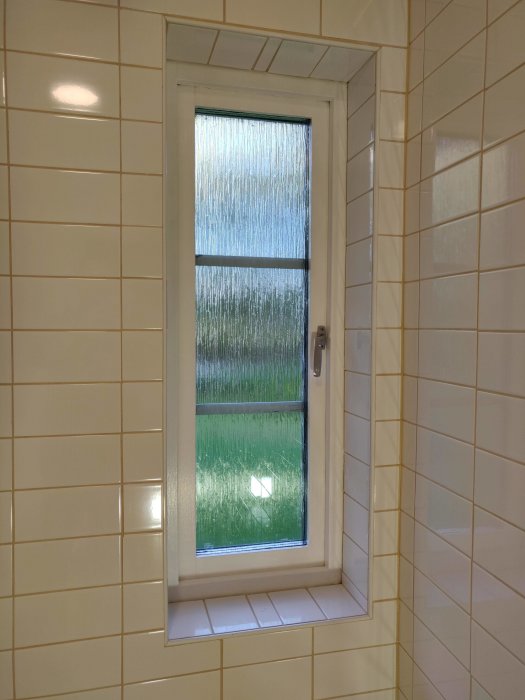 Nymålad vit fönsterram och fönsterkarm i ett kaklat rum med öppet fönster och utsikt till grönt område.