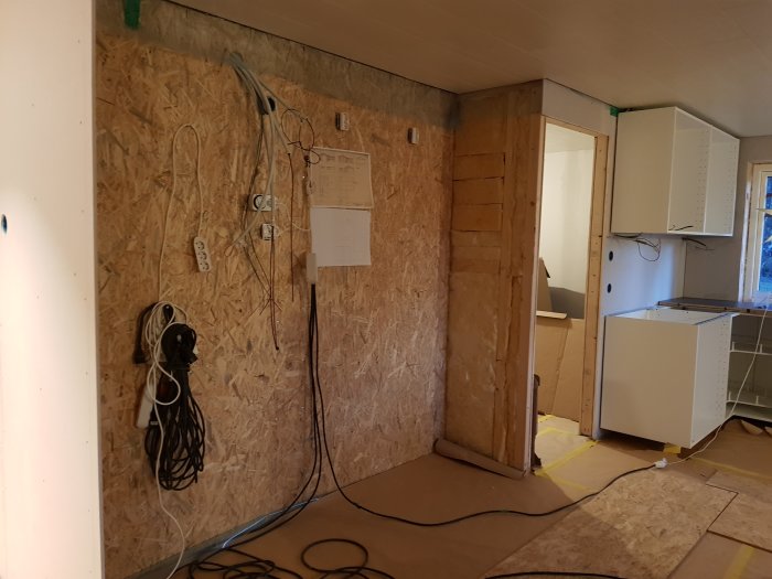 Köksrenovering pågår med osammanfogade skåpstommar och exponerad elinstallation mot OSB-vägg.