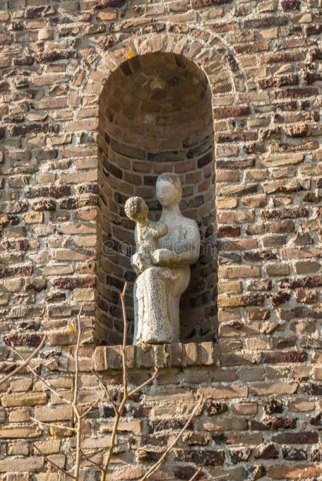 Skulptur av en person och ett barn i en nisch i en tegelvägg.