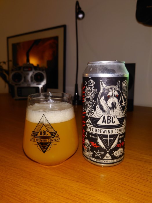 Ölglas fyllt med guldfärgad öl bredvid en ölburk med en varg och grafiska element på etiketten.