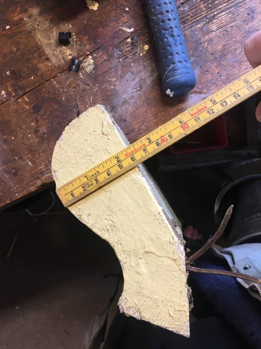 Måttband mäter en specialtillverkad träprofil på ett arbetsbord.