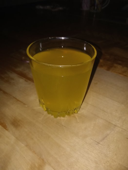 Ett glas med gulaktig dryck på ett träbord, kopplat till en klassisk återupplivad läsk.
