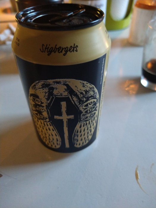 Öppnad ölburk av märket Stigbergets med detaljerad design på etiketten, står på ett bord.