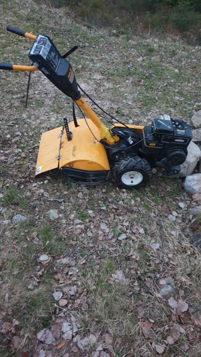 Poulan PPRT5B rotavator parkerad på en höstklädd mark, med dess gula kåpa och svarta motor tydligt synlig.