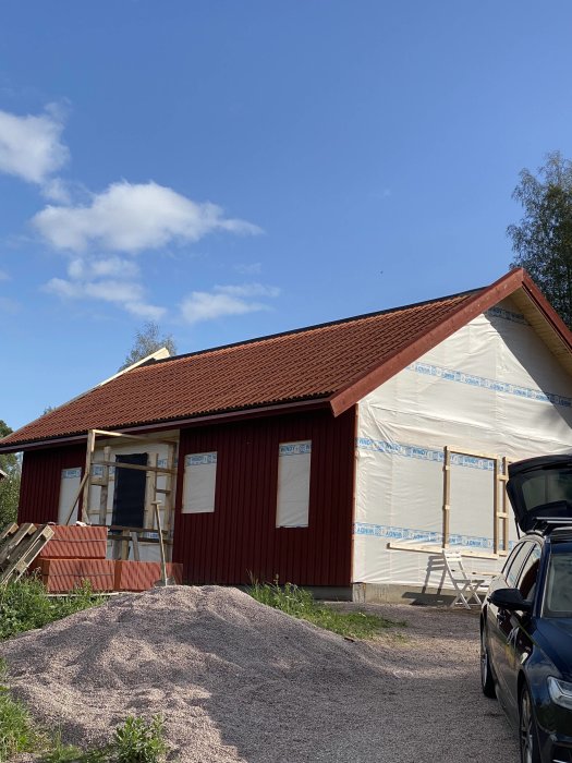 Nytt rött lertegeltak på hus under renovering, synligt avstånd mellan tegelpannor från en vinkel.