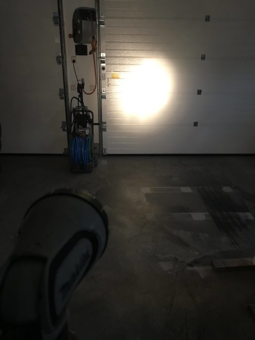 Garage med upplyst vägg av nyinstallerad 12W LED-lampa och synliga verktyg i förgrunden.