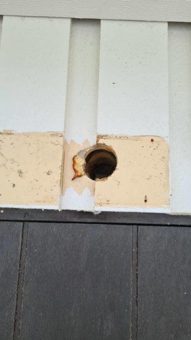 Hål i en vit träfasad där en luftvärmepump tidigare varit installerad.