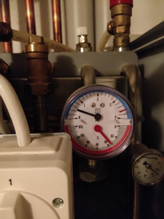 Manometer som visar 0,5 bar tryck i en värmeanläggning med synliga rörkopplingar och ventiler.