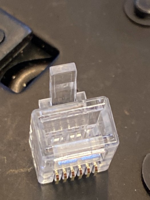 Transparent RJ45-kontakt med obestämd pin-konfiguration på mörkt underlag.