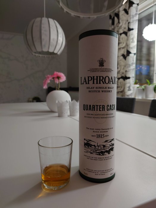 Flaska av Laphroaig Quarter Cask whisky bredvid ett whiskeyglas, på ett hemmakök.