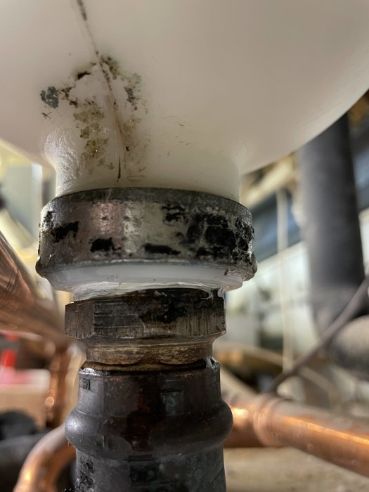 Spricka i expansionskärl med synlig förlust av vätska och bakgrunden visar rörinstallationer.