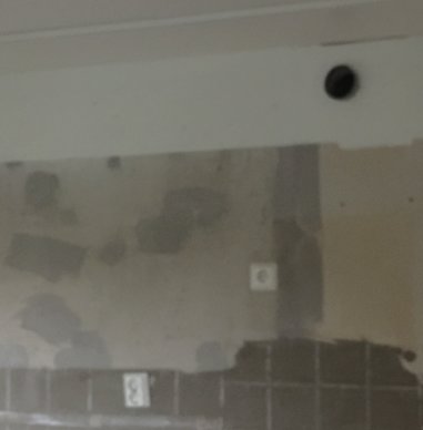 Ventilationsböj som sticker ut från en vägg i ett renoveringsprojekt för kök, med synlig kakel och spacklade ytor.