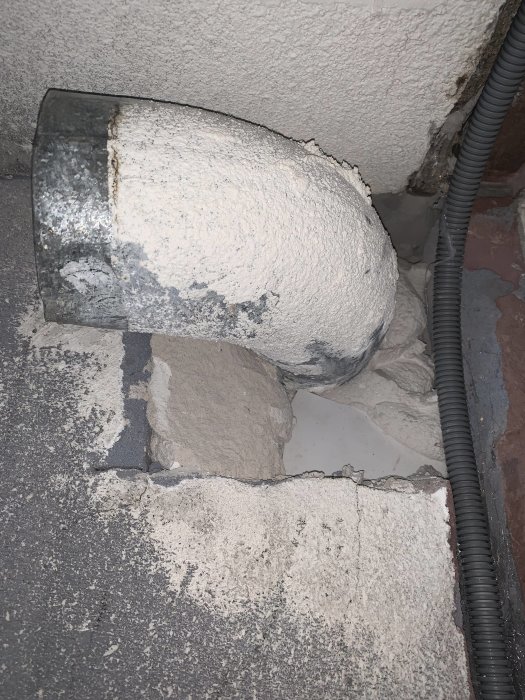 Ventilationsböj i galvaniserat material utskjutande från en vägg i ett renoveringsobjekt vid en köksrenovering.