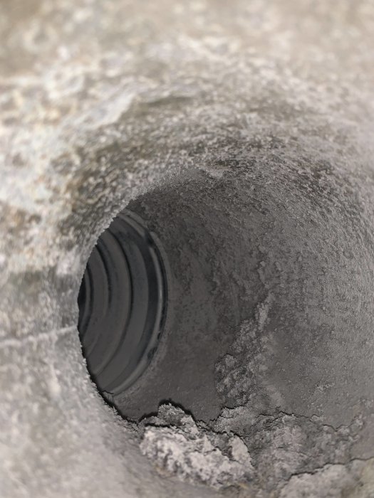 Ventilationsböj inuti en grå betongvägg efter borttagning av förlängningsrör under köksrenovering.