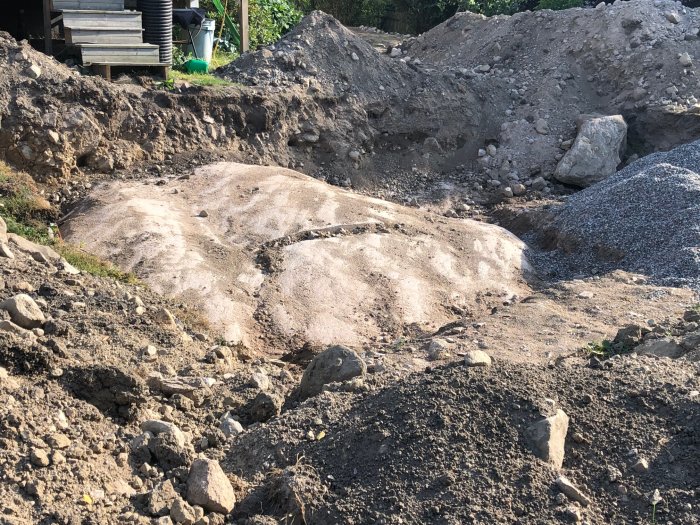 Grus- och jordhög samt grävda gropar vid en byggarbetsplats.