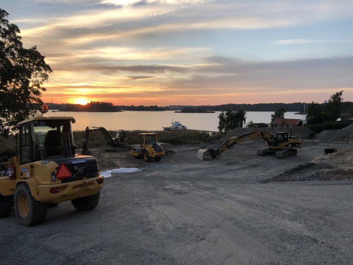 Byggplats med maskiner vid solnedgång längs kusten, indikerar starten på ett nytt byggprojekt.