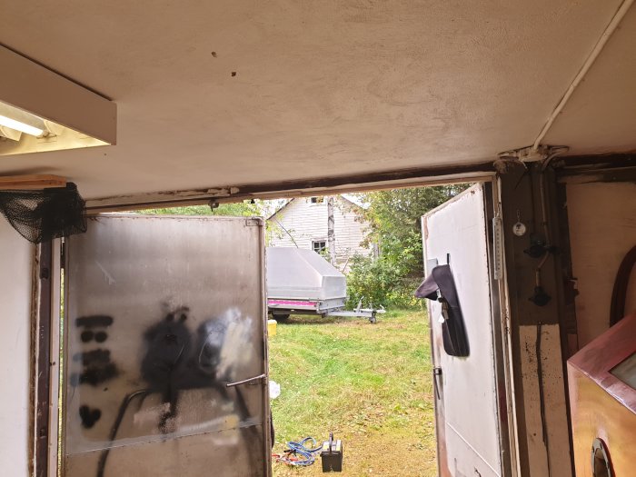 Interiör av källargarage med två öppna portar, takhöjd 218 cm, och synlig pelare mellan portarna.