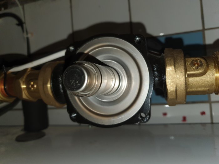 Cirkulationspump avmonterad för underhåll, motordel synlig och rörsystem i bakgrunden.