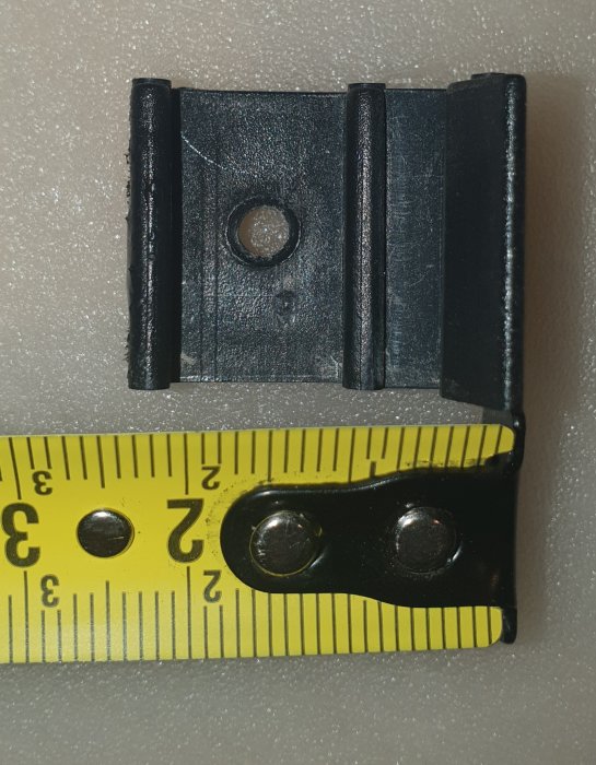 Sprucket plastclip för fönster bredvid en mätkniv för storleksjämförelse.