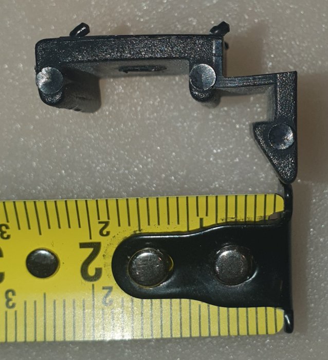 Sprucket fönsterplastclip bredvid en måttstock för storleksjämförelse.