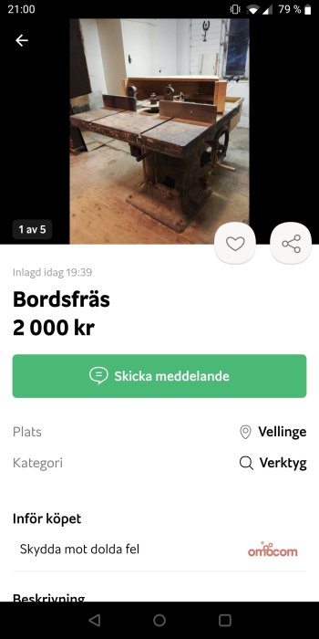 Gammal bordfräs på trägolv i ett verkstadsutrymme.