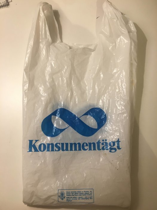 Gammal vit plastpåse med blå logotyp för "Konsumentägt" och text varning om nedbrytning.